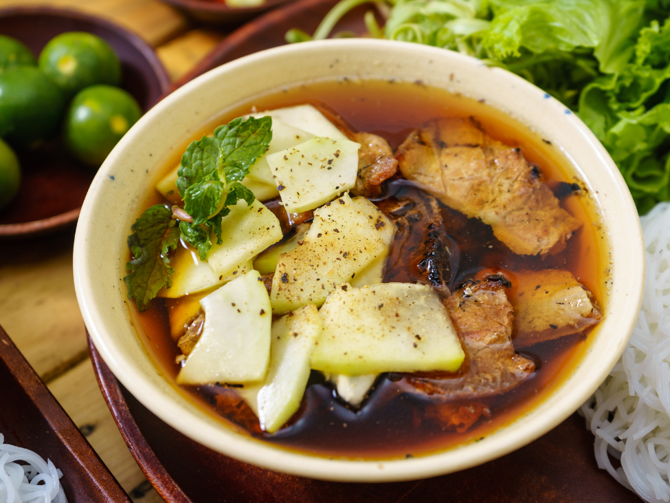 A bowl of Bun Cha with grilled pork, noodles, and herbs.