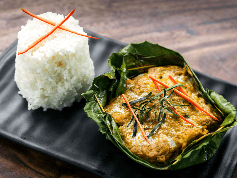 Cambodian amok curry served in a banana leaf bowl with fresh herbs and rice in Siem Reap.