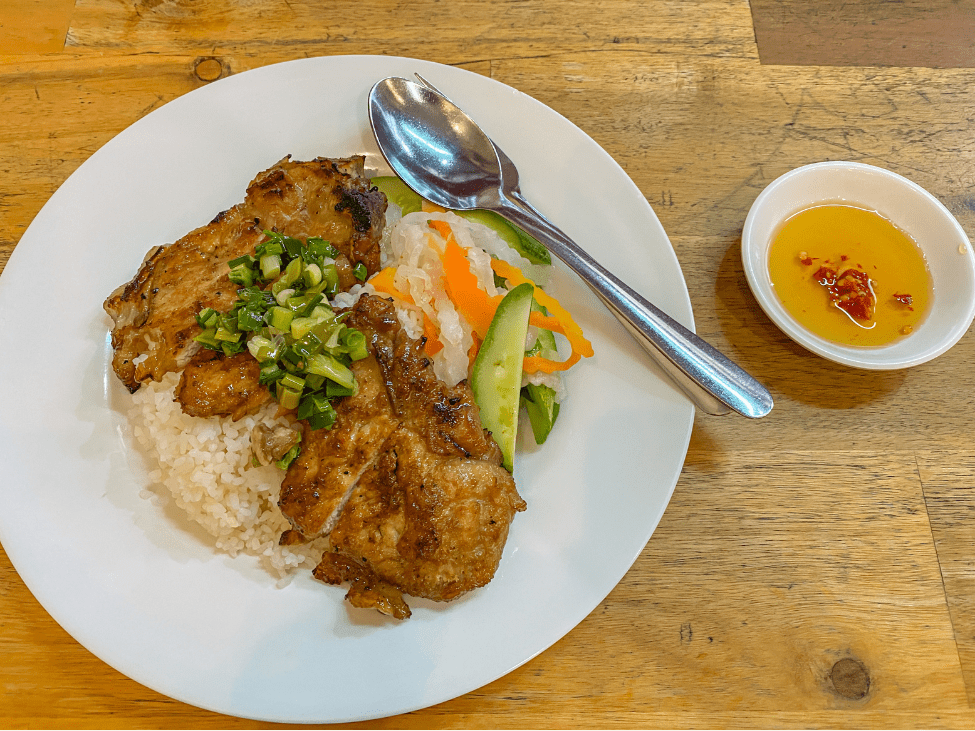 A plate of Com Tam with grilled pork, egg, and pickles.