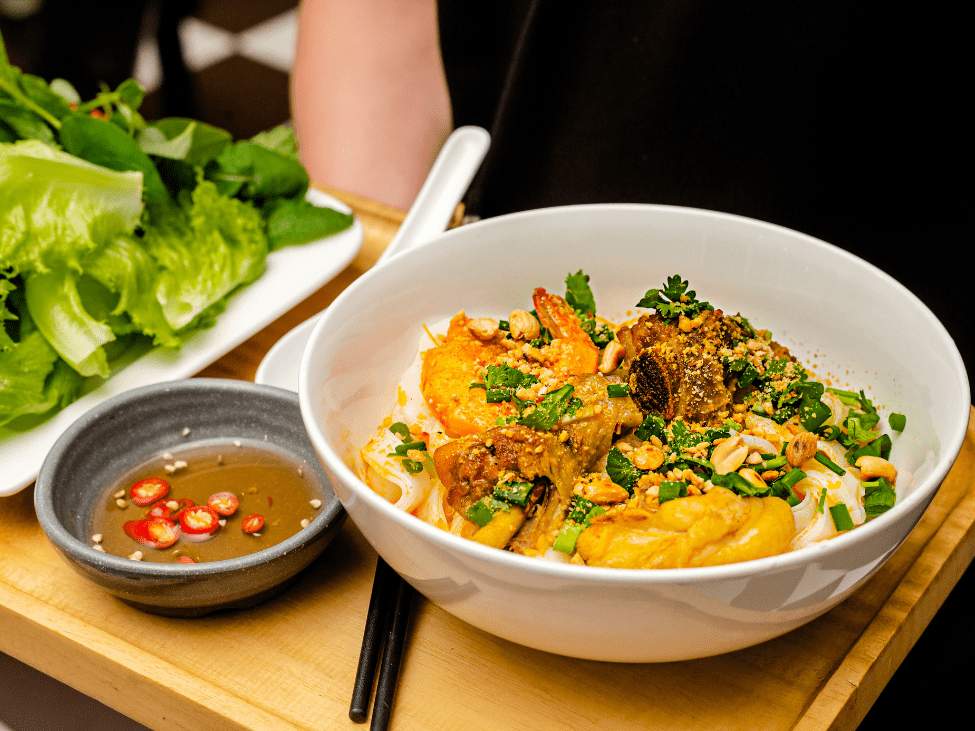 Mi Quang noodles topped with shrimp, pork, and peanuts.