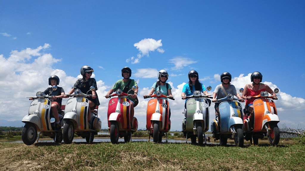 A Vespa tour group exploring a historic village.