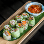 Vietnamese fresh spring rolls served with peanut dipping sauce on a bamboo platter.