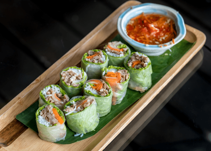 Vietnamese fresh spring rolls served with peanut dipping sauce on a bamboo platter.